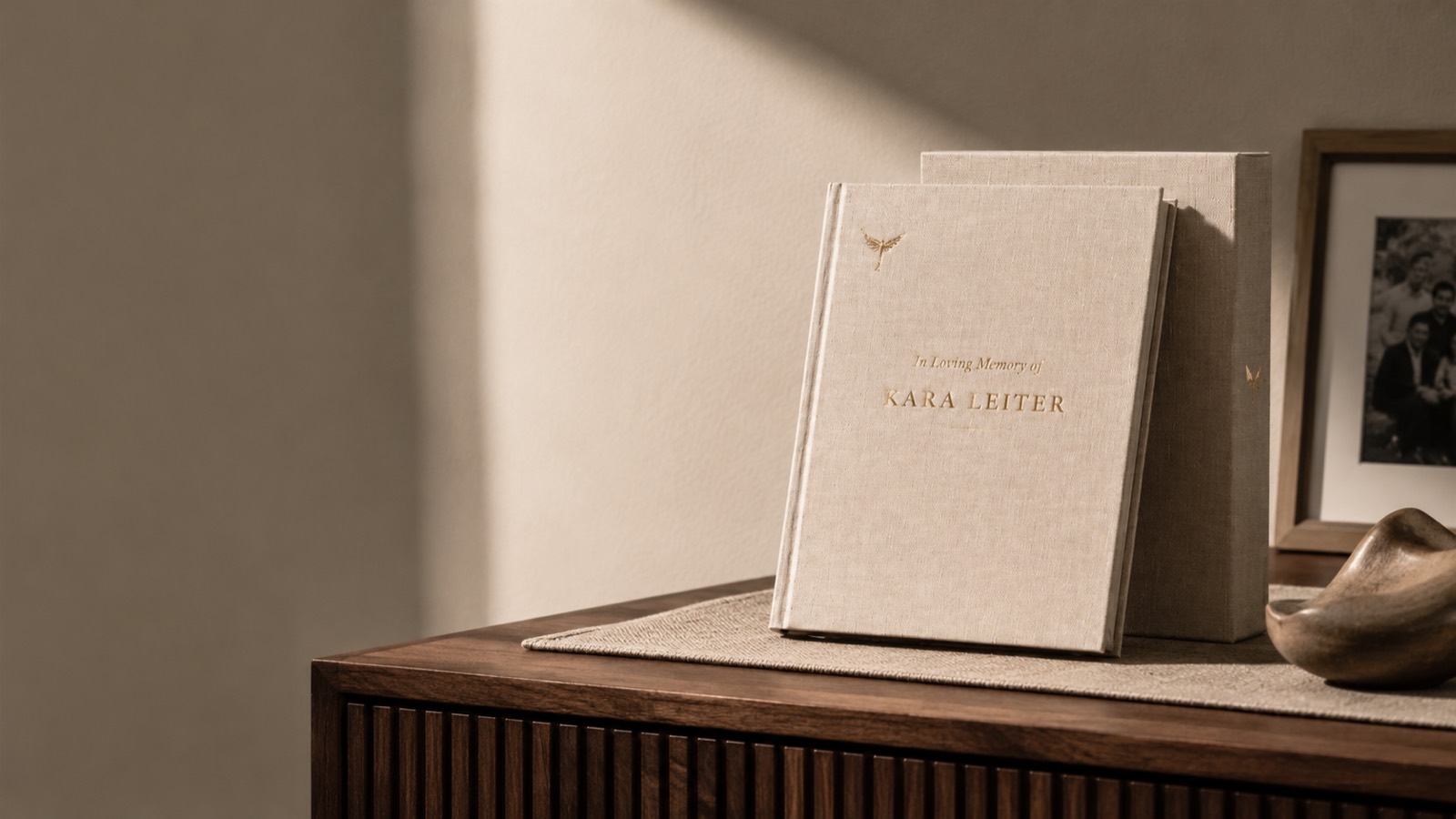 The finished book and its slipcase standing on a walnut credenza beside a framed family picture — the heirloom in the room where it will live.